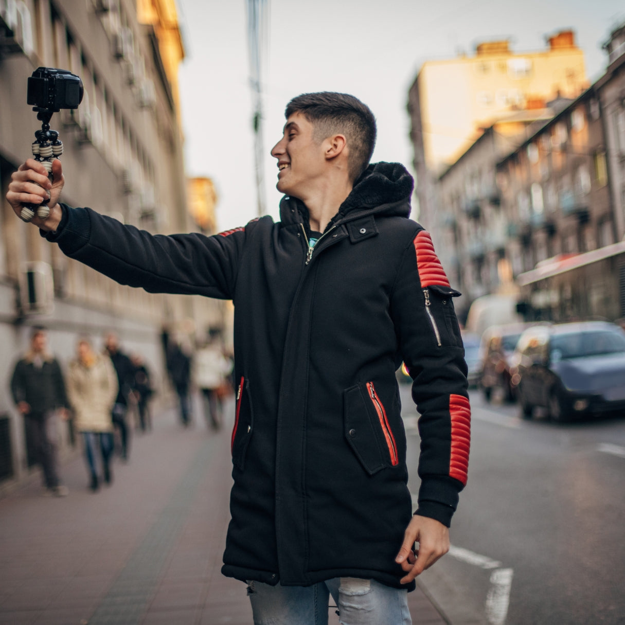 Young man filming vlog on urban city street with camera and backpack
